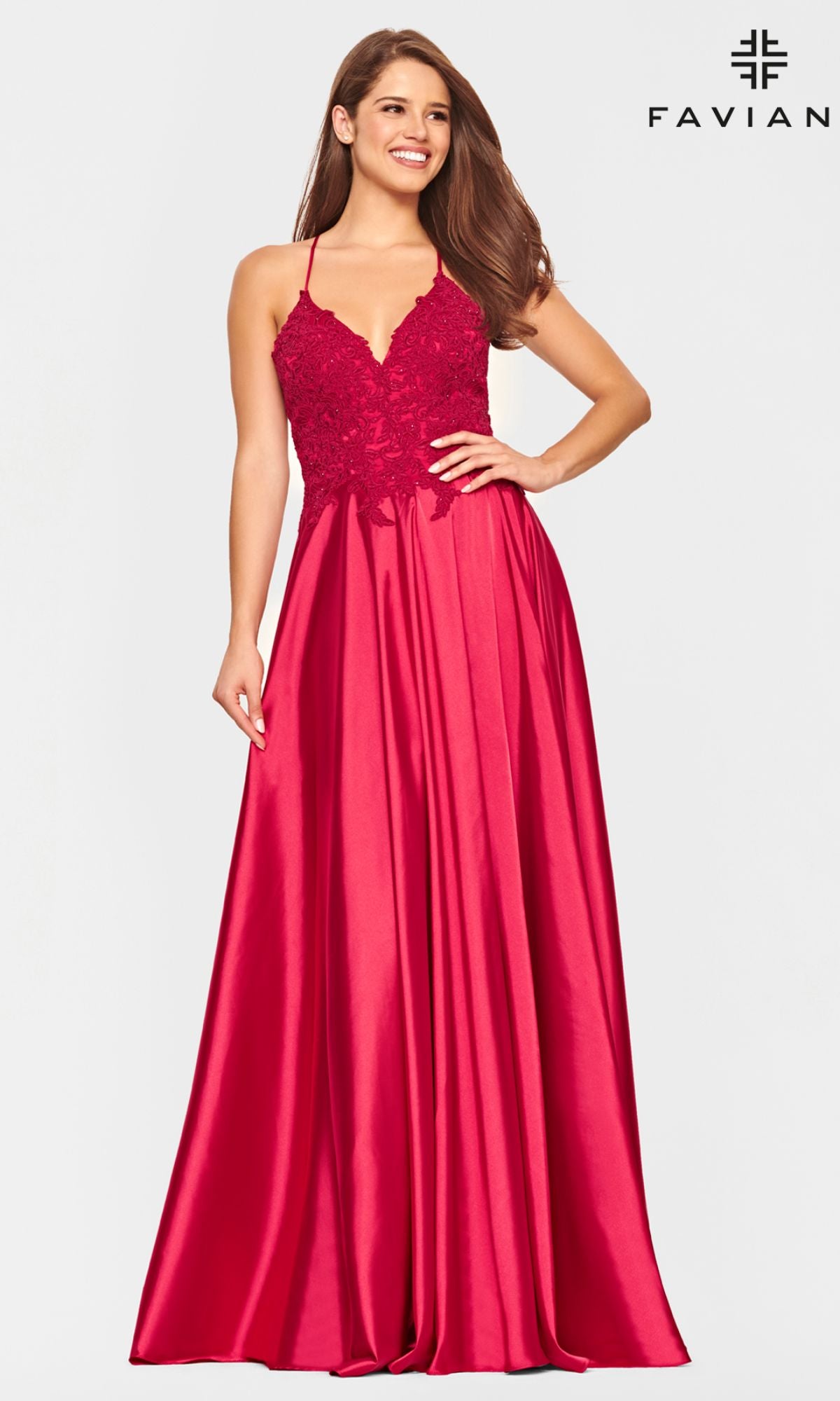 A woman poses and smiles in the Faviana Lace-Bodice Long A-Line Prom Dress, featuring a sleeveless red satin design with floor-length skirt and embroidered lace bodice, set against a plain light background.